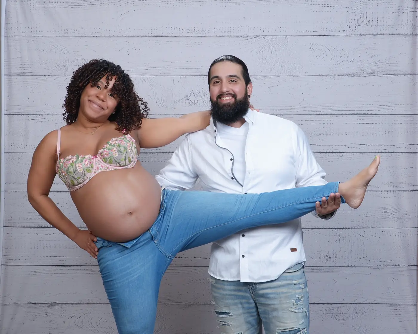 A couple posing and laughing; she is pregnant