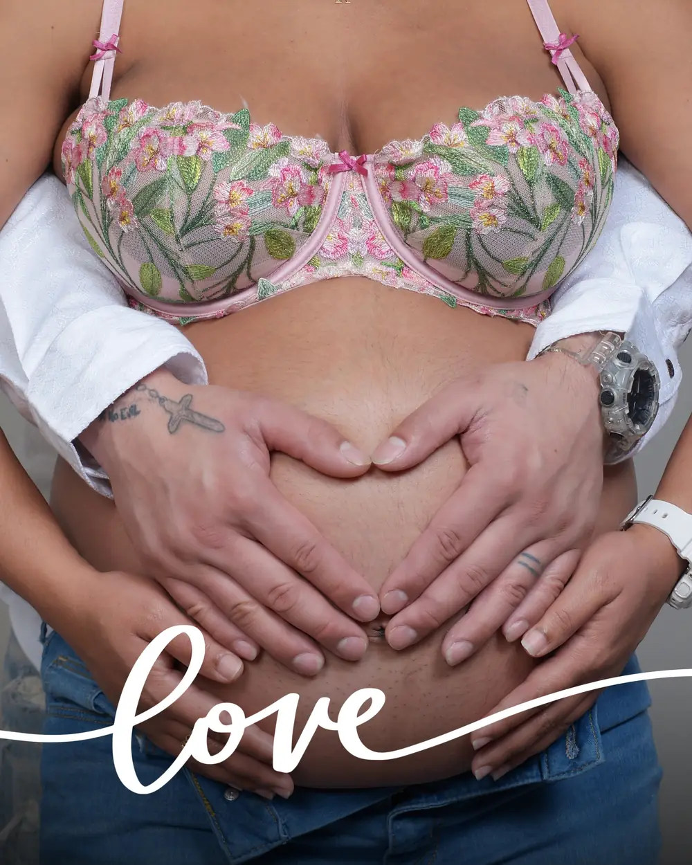 A couple's hands forming a heart over the pregnant belly