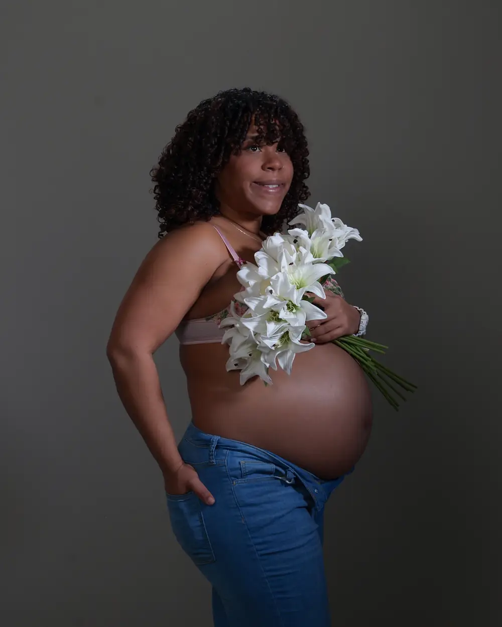 A pregnant mother holding a bunch of white lilies